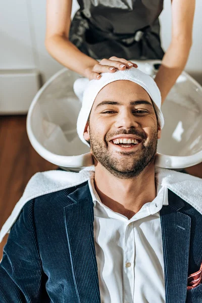 Abgeschnittene Aufnahme von Friseur, der im Schönheitssalon dem glücklichen schönen Mann die Haare wäscht — Stockfoto