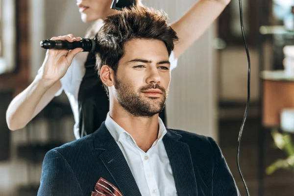 Tiro cortado de penteado penteado e secagem de cabelo para jovem bonito no salão de beleza — Fotografia de Stock