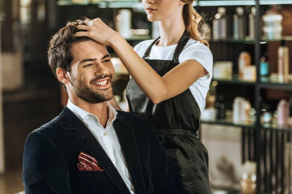 Plan recadré de jeune coiffeuse faisant coiffure à bel homme souriant dans le salon de beauté — Photo de stock