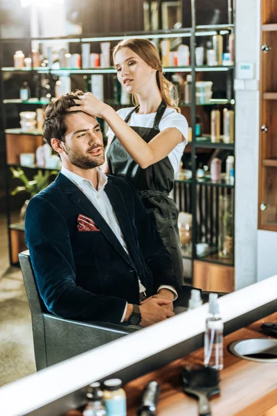 Молодая женщина парикмахер делает прическу красивому мужчине в салоне красоты — стоковое фото