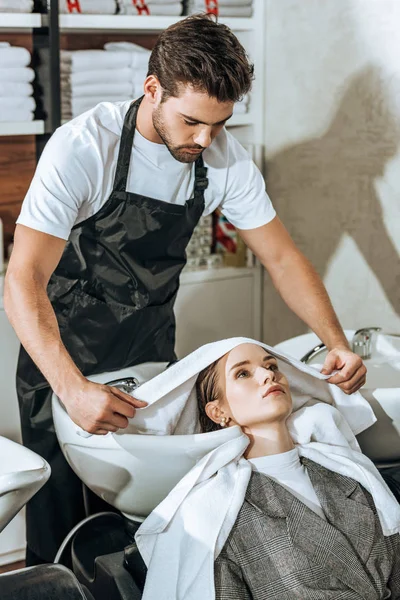 Bello giovane parrucchiere lavare i capelli alla bella donna nel salone di bellezza — Foto stock