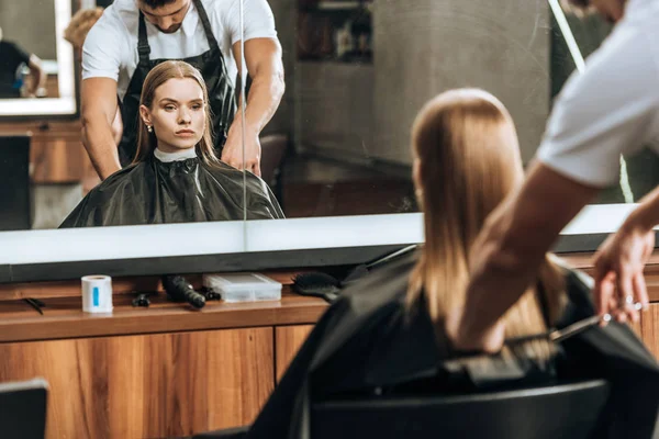 Hairstylist cutting hair to beautiful young woman in beauty salon — Stock Photo