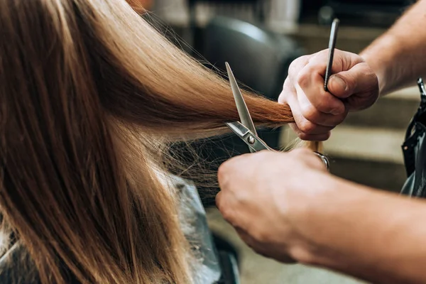 Recortado tiro de peluquero haciendo corte de pelo a la mujer joven en salón de belleza - foto de stock