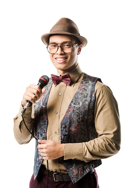 Hombre de raza mixta positivo en sombrero y anteojos cantando en micrófono aislado en blanco - foto de stock