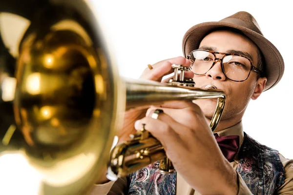 Selektiver Fokus eines jungen gemischten Rassenmannes mit stylischem Hut und Brille, der isoliert auf weißer Trompete spielt — Stock Photo