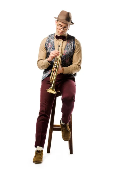 Stylish male jazzman holding trumpet and sitting on chair isolated on white — Stock Photo