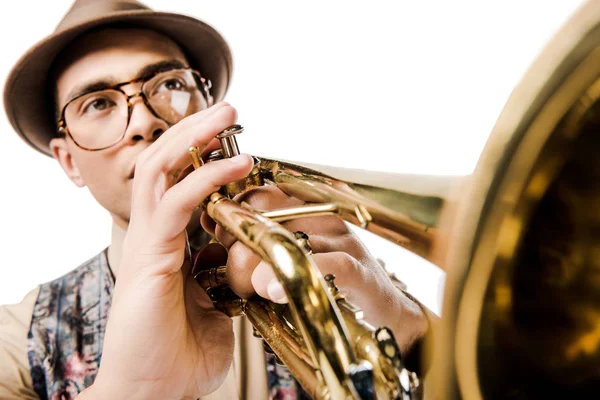 Foco seletivo de mestiço músico masculino em chapéu elegante e óculos tocando trompete isolado em branco — Fotografia de Stock