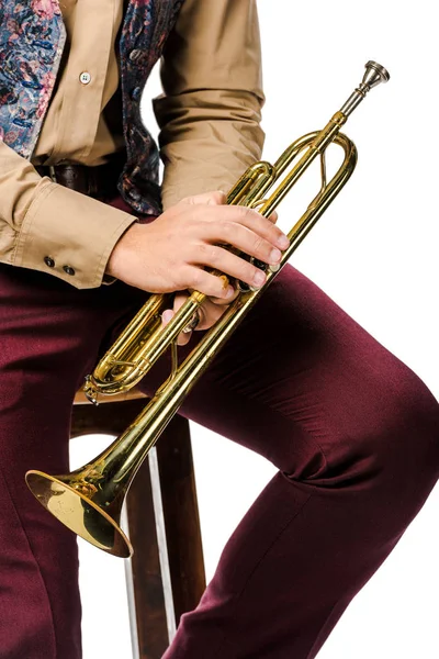 Image recadrée de jazzman mâle tenant la trompette et assis sur la chaise isolé sur blanc — Photo de stock