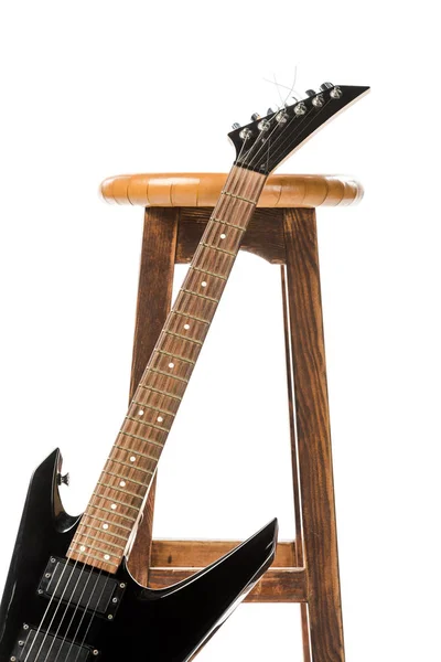 Nahaufnahme einer schwarzen E-Gitarre in der Nähe eines Holzstuhls isoliert auf Weiß — Stockfoto