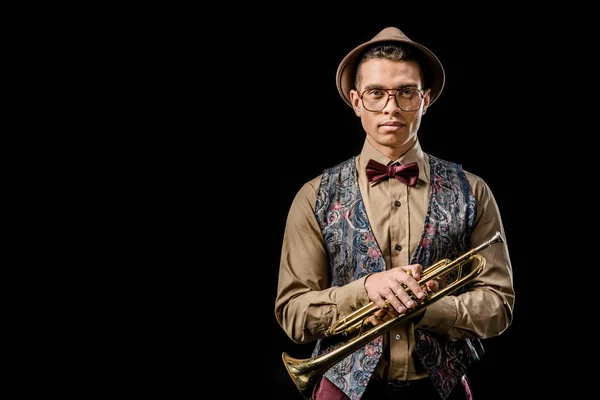 Стильний молодий чоловічий музикант позує з трубою ізольовано на чорному — стокове фото
