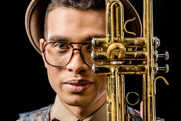 Close up portrait of young male musician posing with trumpet isolated on black — Stock Photo