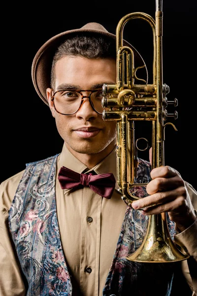 Retrato de un joven músico elegante posando con trompeta aislada sobre negro - foto de stock