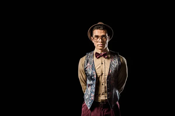 Élégant jeune modèle masculin en gilet et noeud papillon posant isolé sur noir — Photo de stock