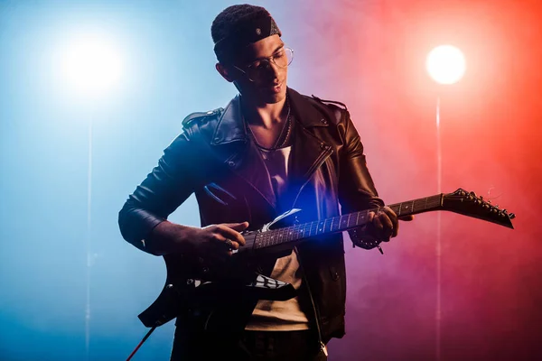 Músico masculino tocando guitarra elétrica no palco com fumaça e iluminação dramática — Fotografia de Stock