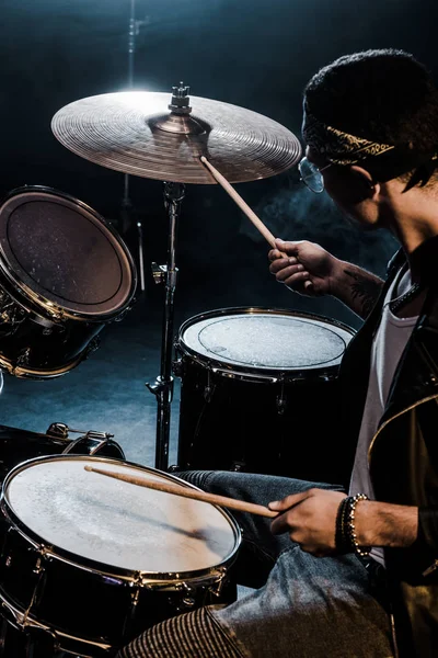 Vista lateral mista raça masculina músico tocando bateria durante concerto de rock no palco — Fotografia de Stock