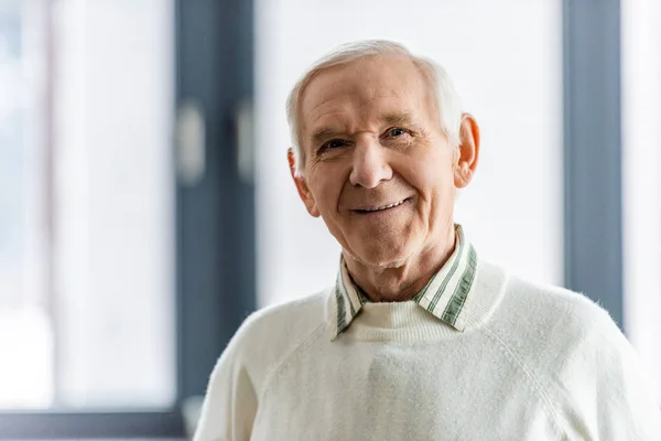 Крупным планом портрет улыбающегося пожилого человека, смотрящего в камеру — стоковое фото
