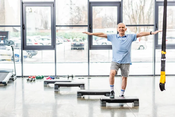 Desportista sênior alegre exercitando na plataforma passo no ginásio — Fotografia de Stock