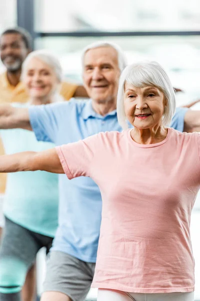 Enfoque selectivo de deportistas senior síncrona haciendo ejercicio en el gimnasio - foto de stock