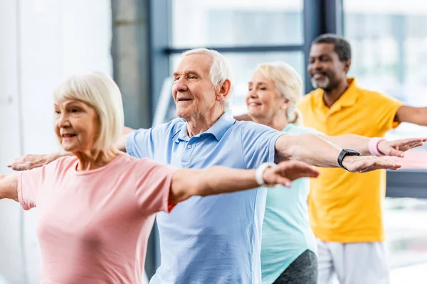 Atletas seniores multiculturais felizes síncronos fazendo exercício no ginásio — Fotografia de Stock