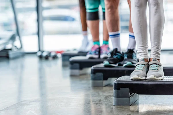 Обрезанные снимки спортсменов, стоящих на ступенчатых площадках в спортзале — стоковое фото
