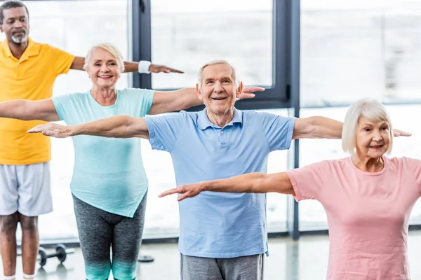 Vista ad alto angolo di atleti anziani multiculturali sincrono fare esercizio in palestra — Foto stock