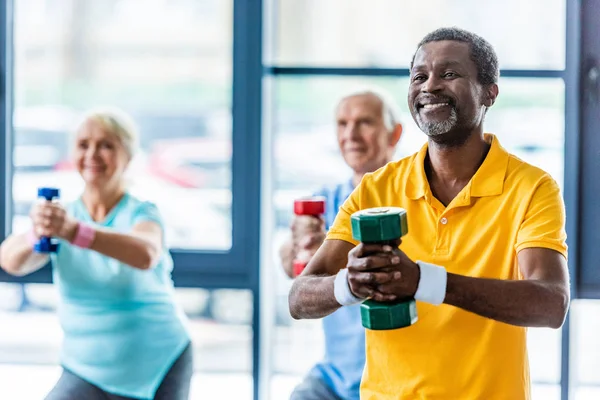 Afroamericano sportivo ei suoi amici che esercitano con manubri in palestra — Foto stock