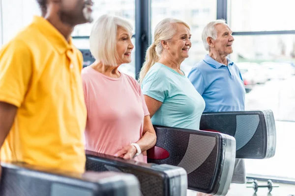 Focus selettivo degli atleti senior che tengono piattaforme passo in palestra — Foto stock