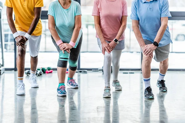 Cropped shot of senior sportspeople synchronous stretching at gym — Stock Photo
