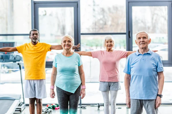 Sportivi anziani multietnici sorridenti che fanno esercizio in palestra — Foto stock