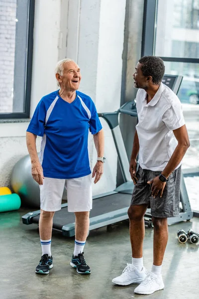 Cheerful multiethnic sportsmen talking to each other at gym — Stock Photo