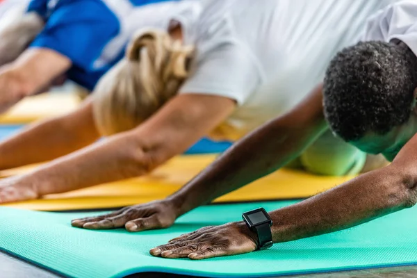 Afro-americano desportista com smartwatch exercitando perto de amigos no ginásio — Fotografia de Stock