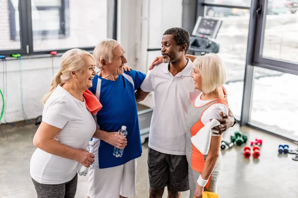 High angle view of happy multicultural senior sportspeople talking and embracing each other at gym — Stock Photo
