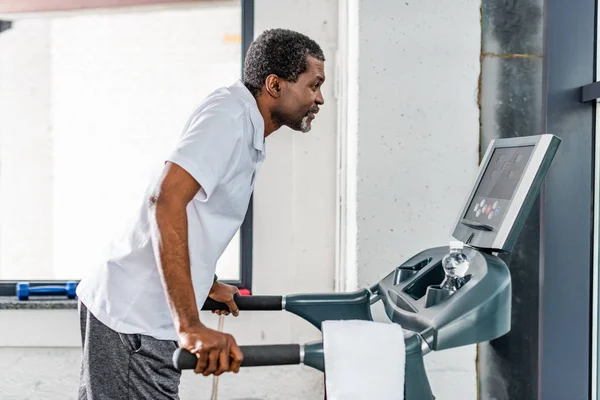 Вид збоку зрілого афроамериканського спортсмена, що біжить на біговій доріжці в спортзалі — стокове фото