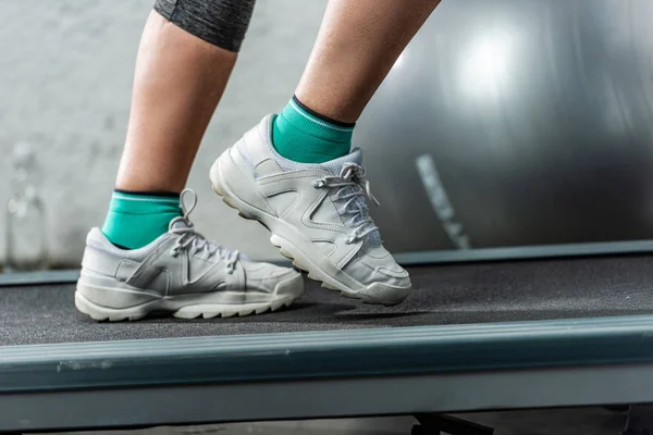 Cropped image of sportswoman running on treadmill at sports hall — Stock Photo