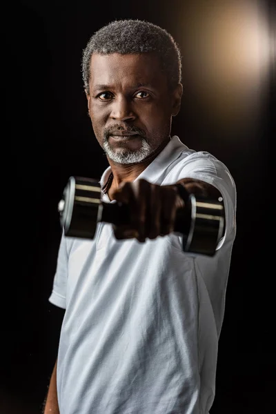 African american mature sportsman exercising with dumbbell on black — Stock Photo