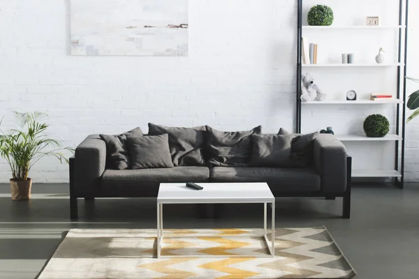 Salon intérieur moderne avec canapé gris, table et étagères — Photo de stock