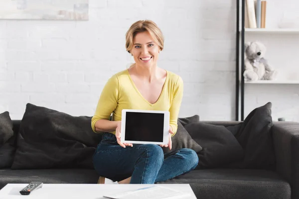 Bela mulher mostrando tablet digital com tela em branco e sorrindo para a câmera — Fotografia de Stock