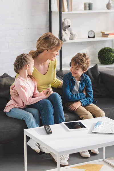 High angle view of happy mother looking at adorable smiling children sitting together on couch — Stock Photo