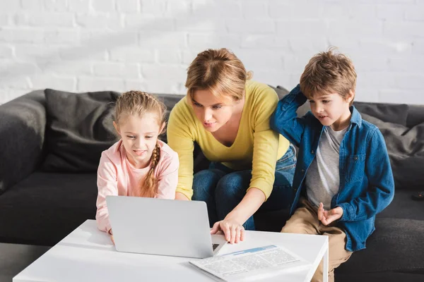 Mother with adorable children using laptop together at home — Stock Photo