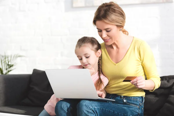 Feliz madre e hija de compras en línea con ordenador portátil y tarjeta de crédito - foto de stock