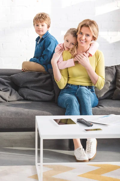 Glückliche Mutter und entzückende kleine Kinder verbringen Zeit miteinander und lächeln in die Kamera — Stockfoto