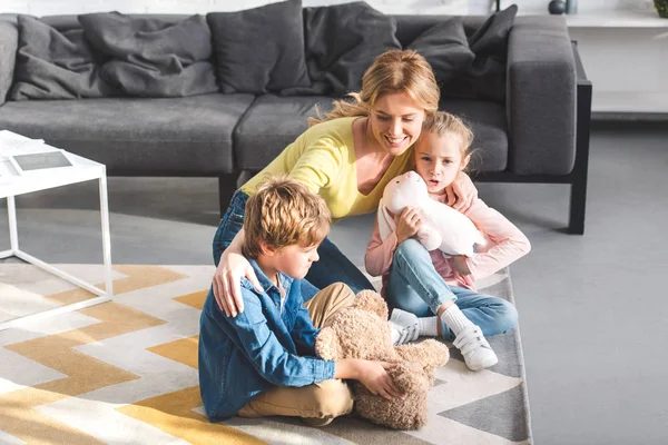 Vista de ángulo alto de la madre feliz con niños pequeños y lindos jugando juntos en casa - foto de stock