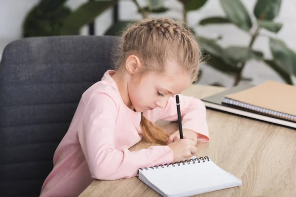 Entzückendes Kind, das am Schreibtisch sitzt und zu Hause lernt — Stockfoto