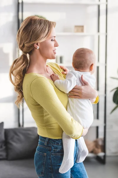 Beautiful mother holding adorable infant child at home — Stock Photo