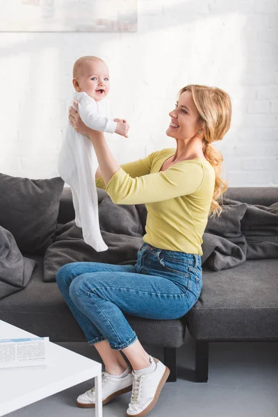 Side view of happy mother holding beautiful infant child at home — Stock Photo