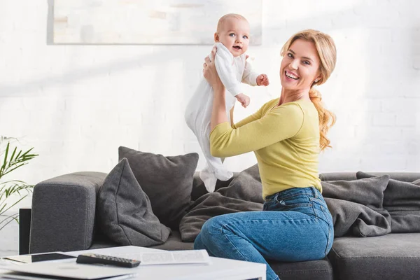 Happy mother holding adorable infant child and smiling at camera — Stock Photo