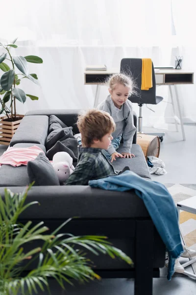 Mignon frère et soeur jouer ensemble sur canapé à la maison — Photo de stock