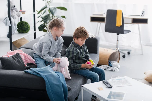 High angle view of siblings sitting on couch and playing with toys at home — Stock Photo