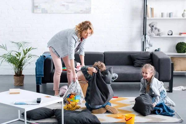 Müde Mutter sieht ungezogene Kinder, die zu Hause mit Kissen kämpfen — Stockfoto