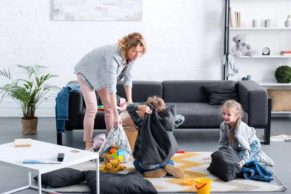 Tired mother looking at naughty kids fighting with pillows at home — Stock Photo